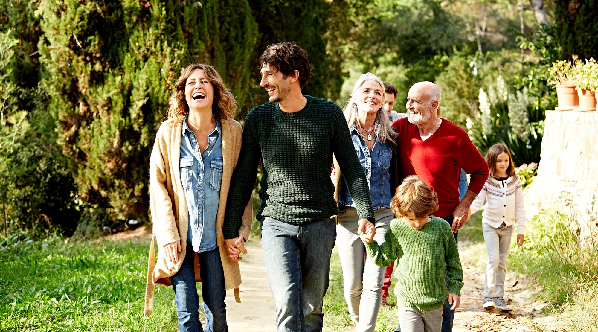 Multi-generational family holding hands while walking outside